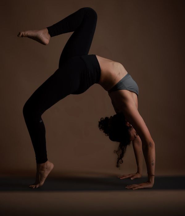 Woman in a calm yoga pose in a studio with dark background and teal light.